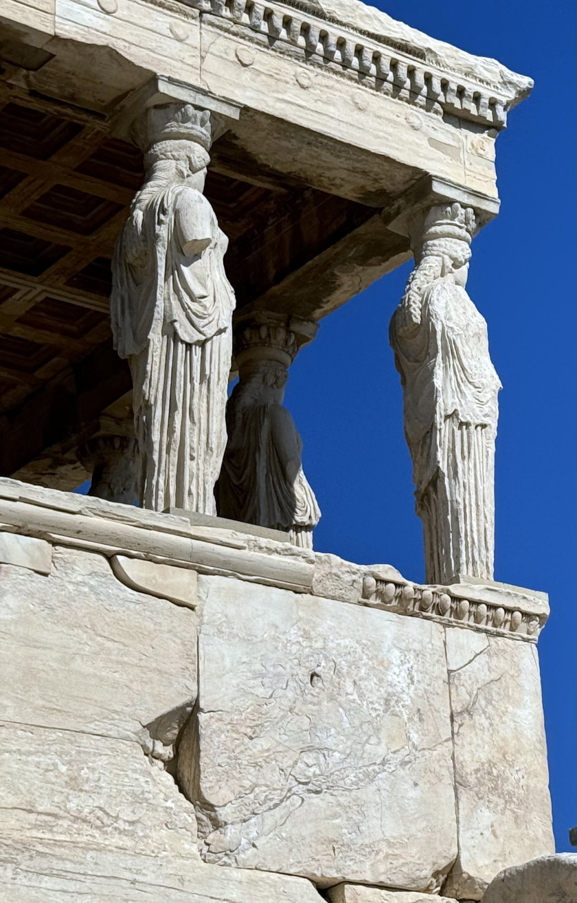 The Caryatid porch of the Erechtheion, at the Acropolis. against a blue sky.