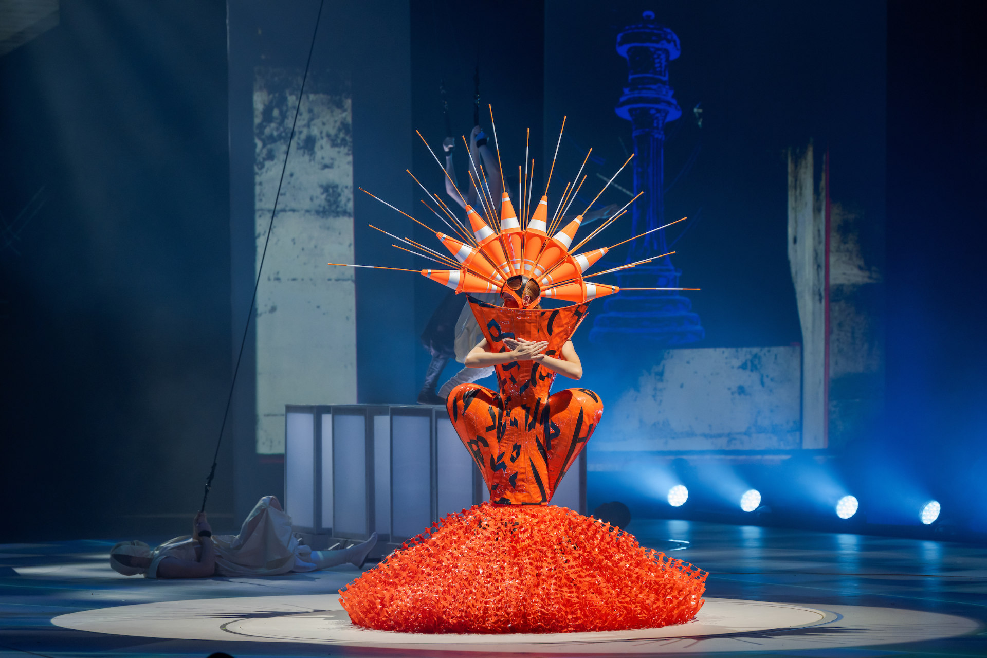 Curves Ahead, wearable art garment in orange, on stage.